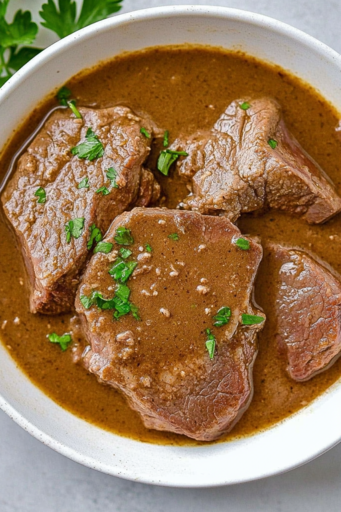 Final dish presentation of juicy beef in savory gravy served in a simple white bowl.