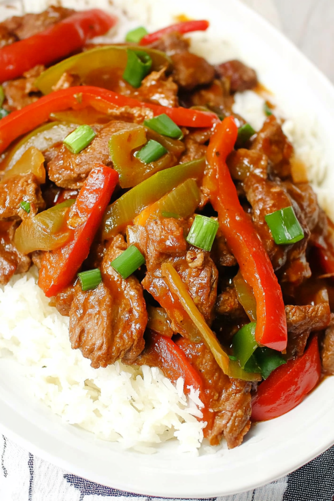 Comforting bowl of saucy beef with colorful peppers served on a bed of steamed rice.