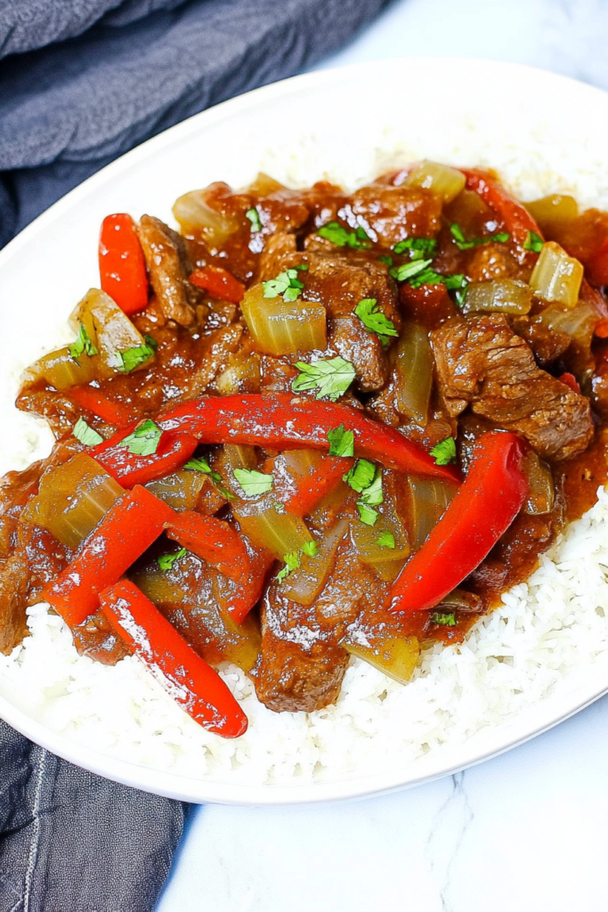 Tender beef strips cooked in a rich savory sauce with sliced bell peppers, served over white rice.