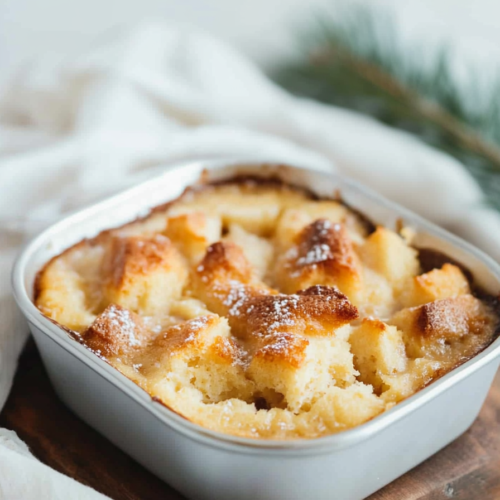 Warm bread pudding with a golden, crisp top served in a small baking dish