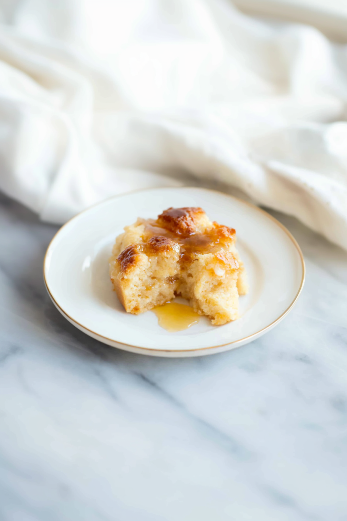 Moist, caramel-topped dessert portion resting on a marble surface with soft fabric in the background.