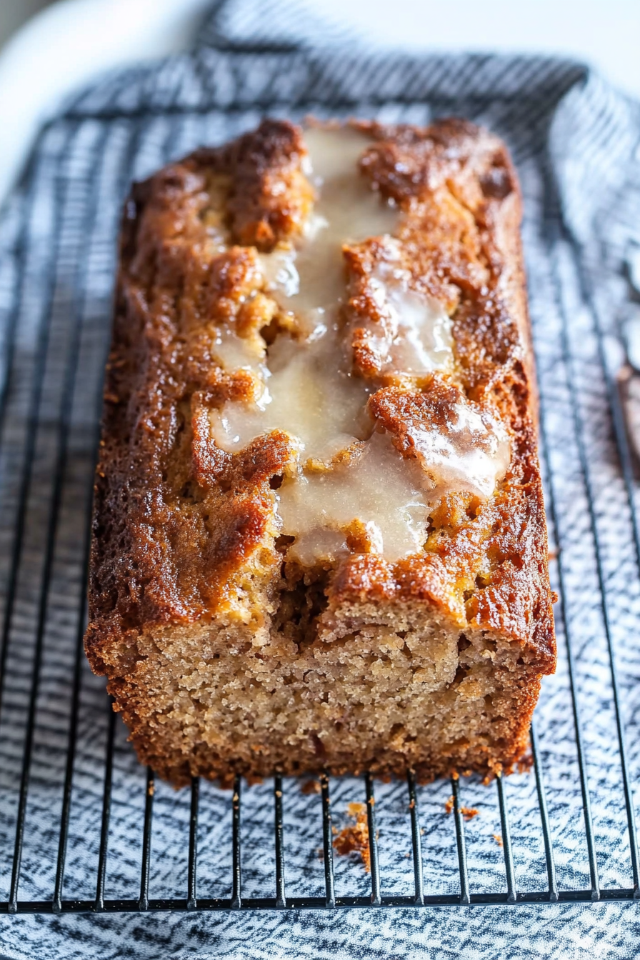 Golden loaf with a drizzle of glaze cooling on a rack.