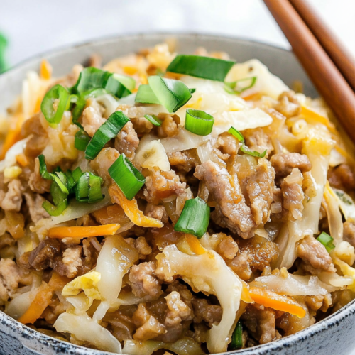 Close-up of a hearty bowl of sautรฉed vegetables and protein, ready to eat with chopsticks.