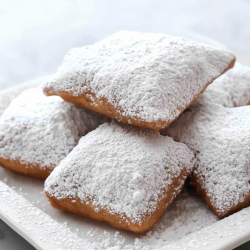 Soft square doughnuts coated in a thick layer of powdered sugar