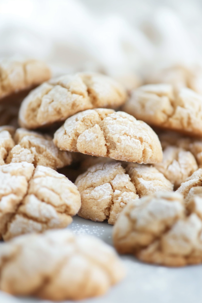 Freshly baked cookies stacked together, highlighting their delicate cracks and sugar dusting.