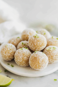 Golden sugar-coated dessert balls stacked on a plate, sparkling under soft light.