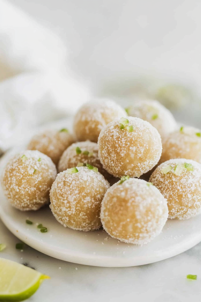 Golden sugar-coated dessert balls stacked on a plate, sparkling under soft light.