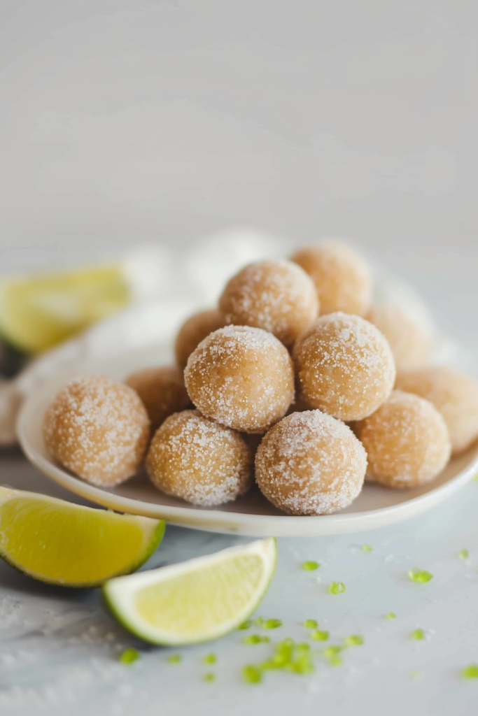 Plate of bite-sized dessert balls, evenly coated in sugar for a festive look.