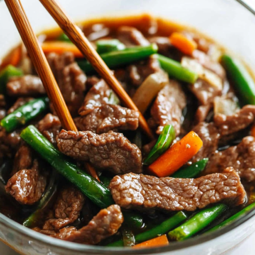 Close-up of saucy Asian-style beef stir fry served with crisp vegetables.