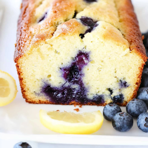 A moist loaf cake bursting with fresh blueberries and a hint of lemon, sliced to show its soft texture.