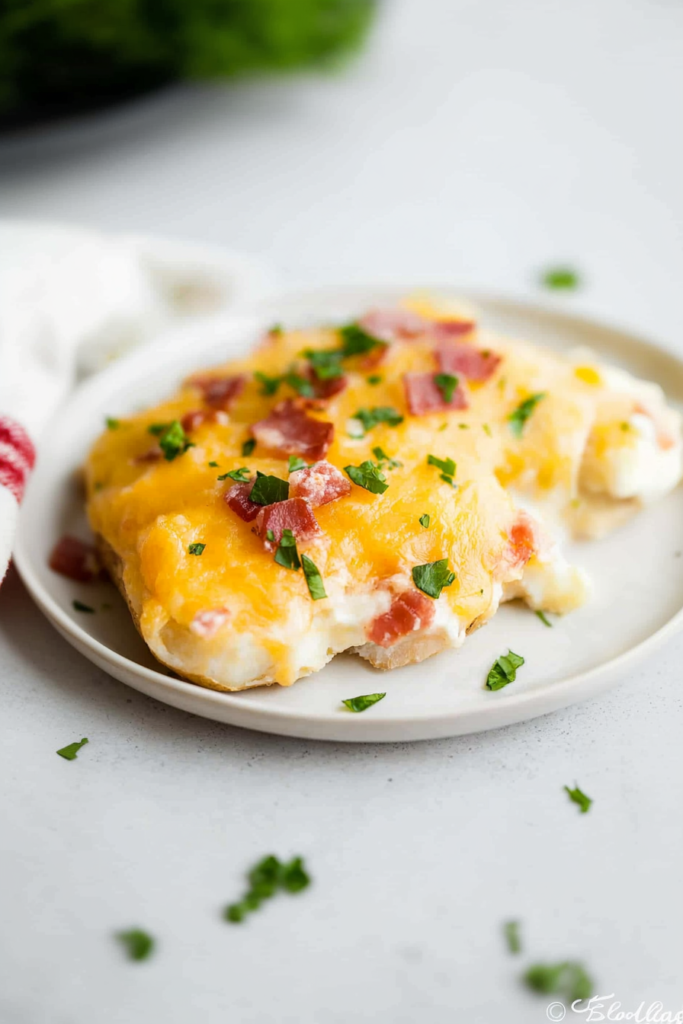 Baked potatoes topped with melted cheddar, crispy bacon bits, and fresh parsley garnish.