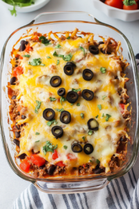 Hearty layered beef dish with peppers, beans, and golden melted cheese