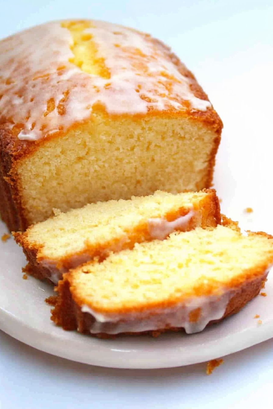 Glazed citrus loaf cake sliced on a plate showing a soft, moist crumb