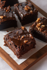 Rich chocolate cake slices with warm frosting served on a wooden board