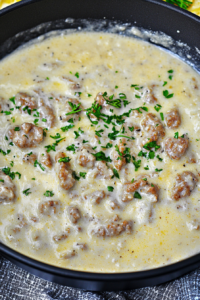 Skillet filled with creamy sausage gravy, garnished with fresh parsley