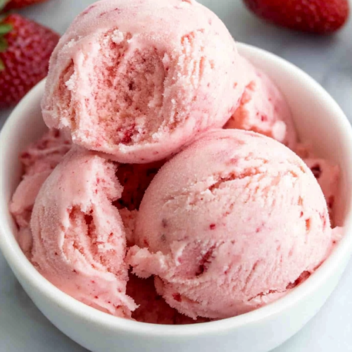 Close-up of homemade ice cream with visible strawberry pieces and smooth texture.
