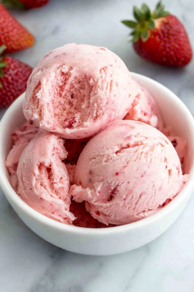 Close-up of homemade ice cream with visible strawberry pieces and smooth texture.