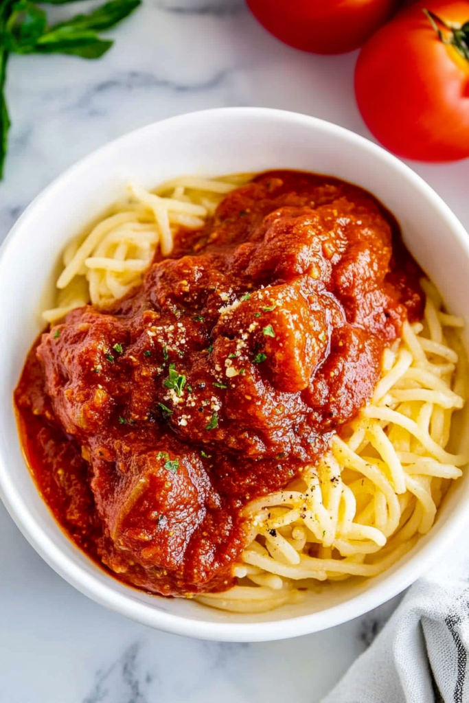 Final plated dish showing meatballs nestled in glossy marinara with a sprinkle of herbs.