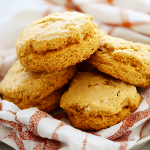 Freshly baked biscuits resting on a checkered cloth, highlighting their tender texture.