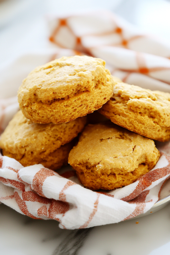 Freshly baked biscuits resting on a checkered cloth, highlighting their tender texture.
