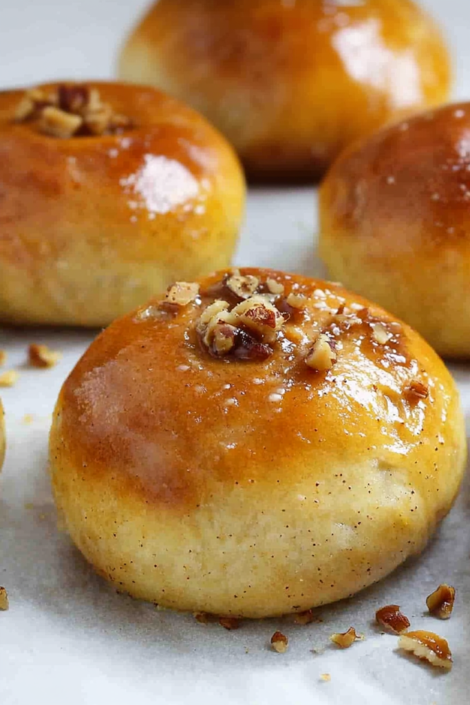 Close-up of fluffy rolls with a shiny glaze, showcasing their tender crumb and nutty topping.