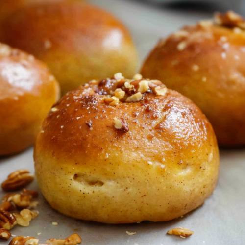 Freshly baked rolls arranged on a light surface, their soft centers highlighted by warm lighting.