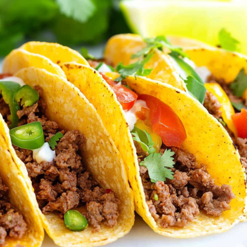 Freshly assembled beef tacos served with cilantro and sliced green chilies.