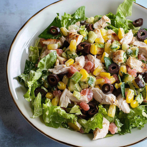 Final plated salad showcasing bright colors, varied textures, and a drizzle of creamy dressing.