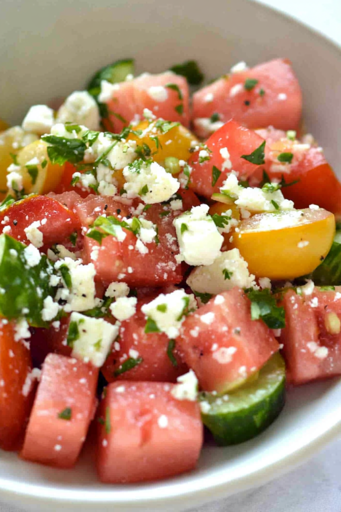 Fresh watermelon and tomato salad topped with crumbled cheese and herbs