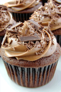 Close-up of frosted chocolate cupcake topped with curls of chocolate shavings
