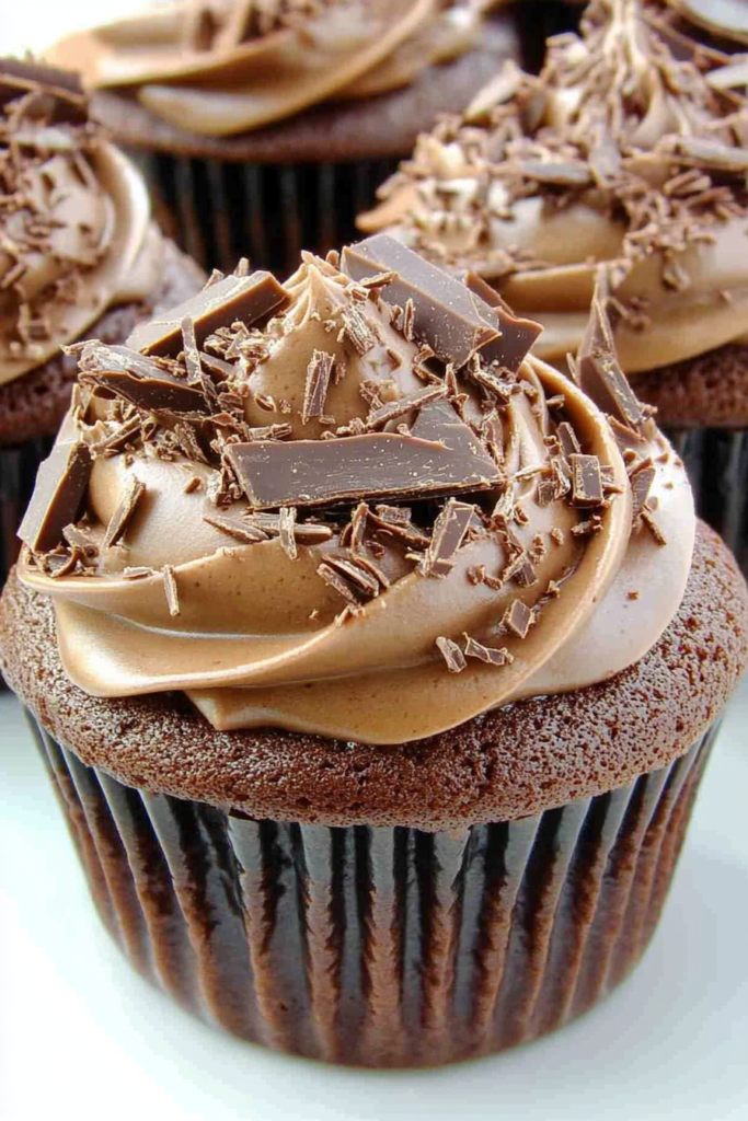 Close-up of frosted chocolate cupcake topped with curls of chocolate shavings