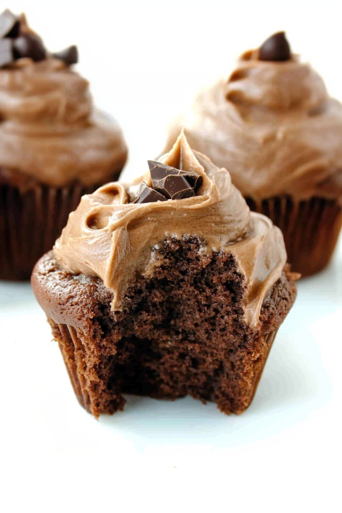 Cupcake with a bite taken out, showing moist chocolate interior and creamy frosting