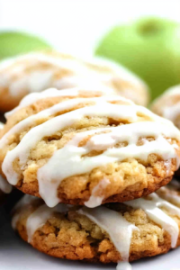 Stack of golden cookies drizzled with glossy vanilla glaze, styled with fresh apples in the background