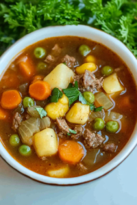 Warm bowl of chunky beef and vegetable soup with herbs and a flavorful broth