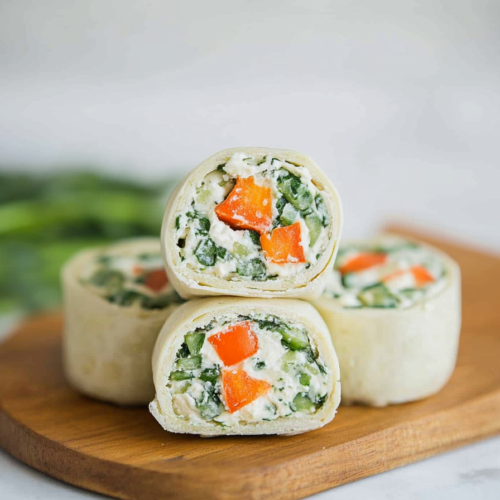 Soft tortilla spirals packed with creamy filling and crisp vegetables, garnished with fresh herbs.