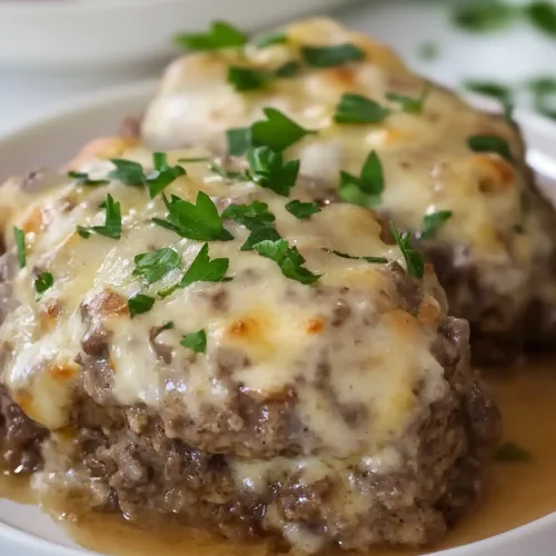 Savory baked hamburger patties served with creamy gravy on a white plate.