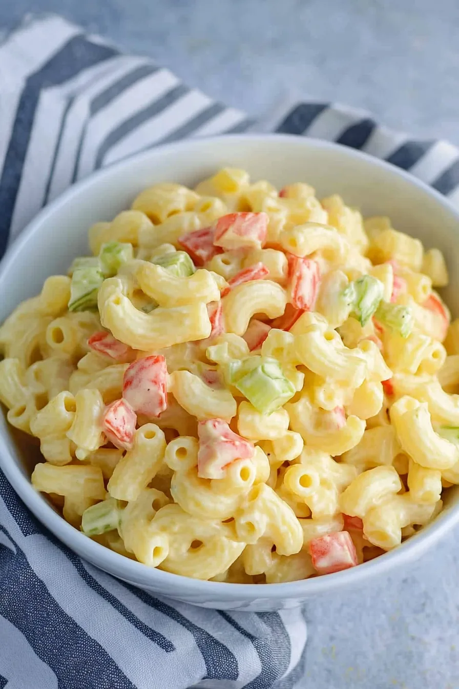 Close-up of tender pasta coated in rich dressing with colorful vegetables.