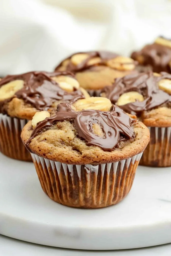 Final plated muffins featuring golden texture, creamy topping, and fresh banana accents.