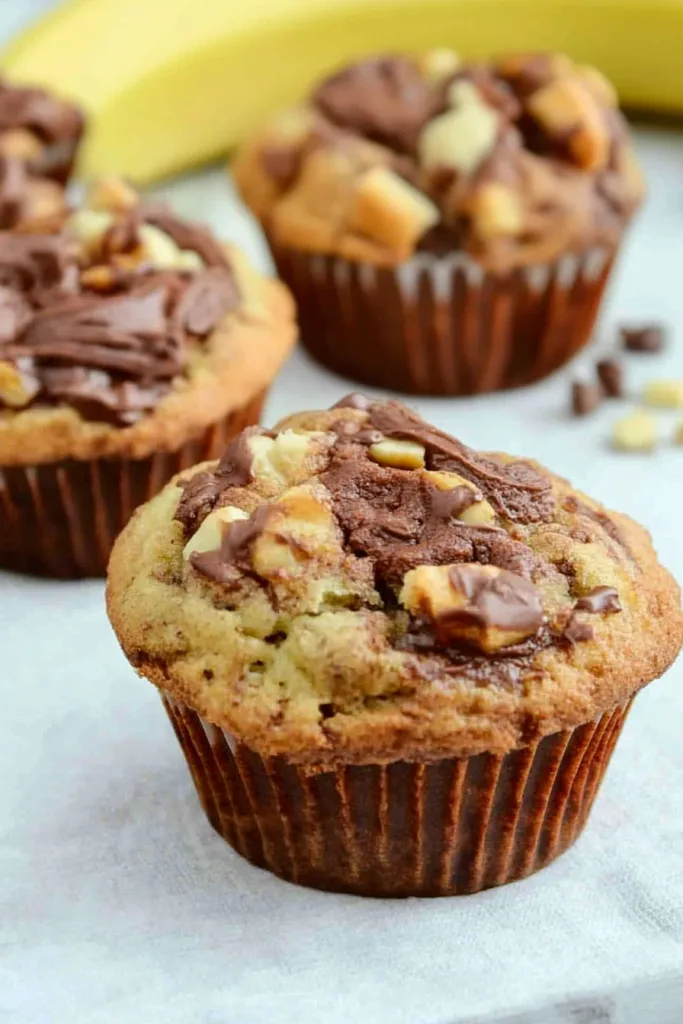 Banana Nutella muffins cooling with shiny chocolate finish and rustic presentation.