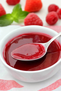 Fresh raspberry and strawberry sauce presented with mint garnish in the background.