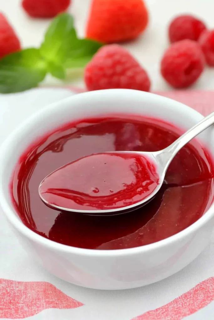 Fresh raspberry and strawberry sauce presented with mint garnish in the background.