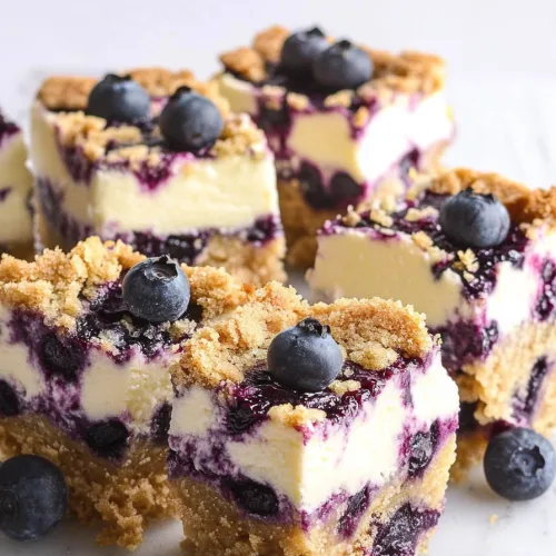Close-up of cheesecake bars showing smooth lemon layer accented by purple-blue fruit swirls.