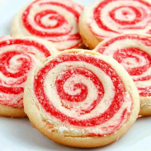 Candy cane pinwheel cookies stacked on a plate, highlighting their vibrant spiral pattern.