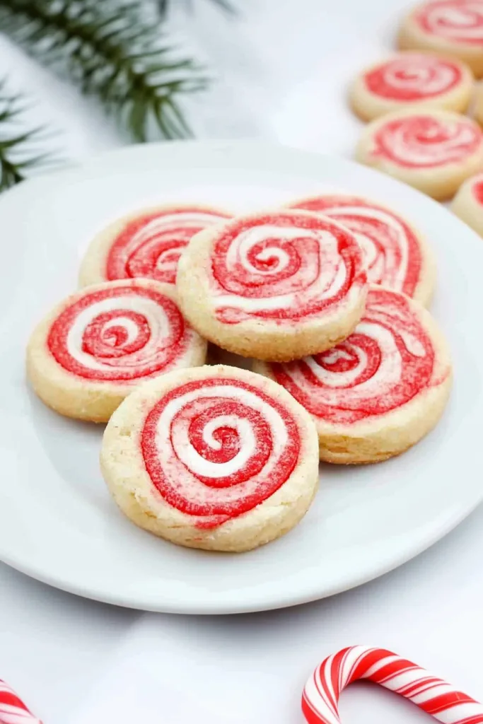Plate of festive red-and-white spiral cookies arranged neatly together.