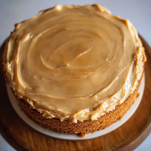 A close-up of a golden sponge cake topped with glossy caramel glaze.