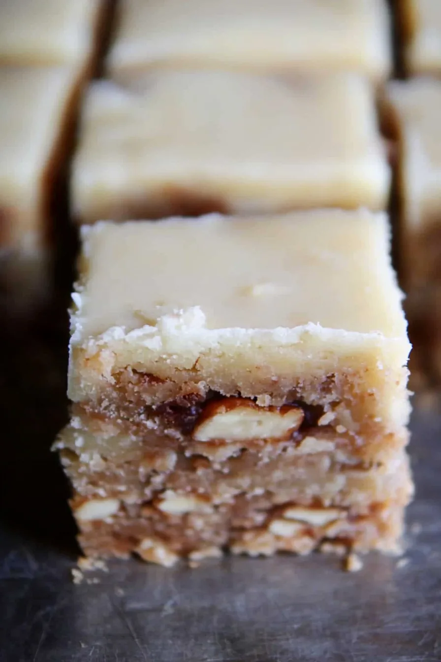 Close-up of rich, nutty bars showing crumbly base and creamy frosting.