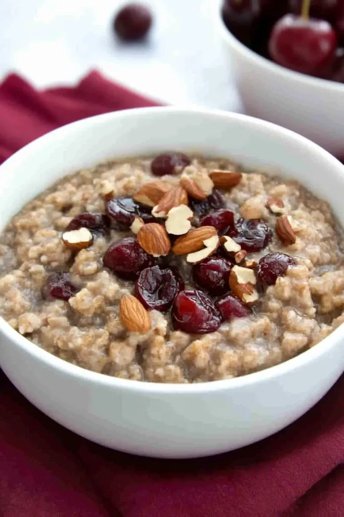 Warm oatmeal served in a white bowl with fruit and nut garnish for texture and color.
