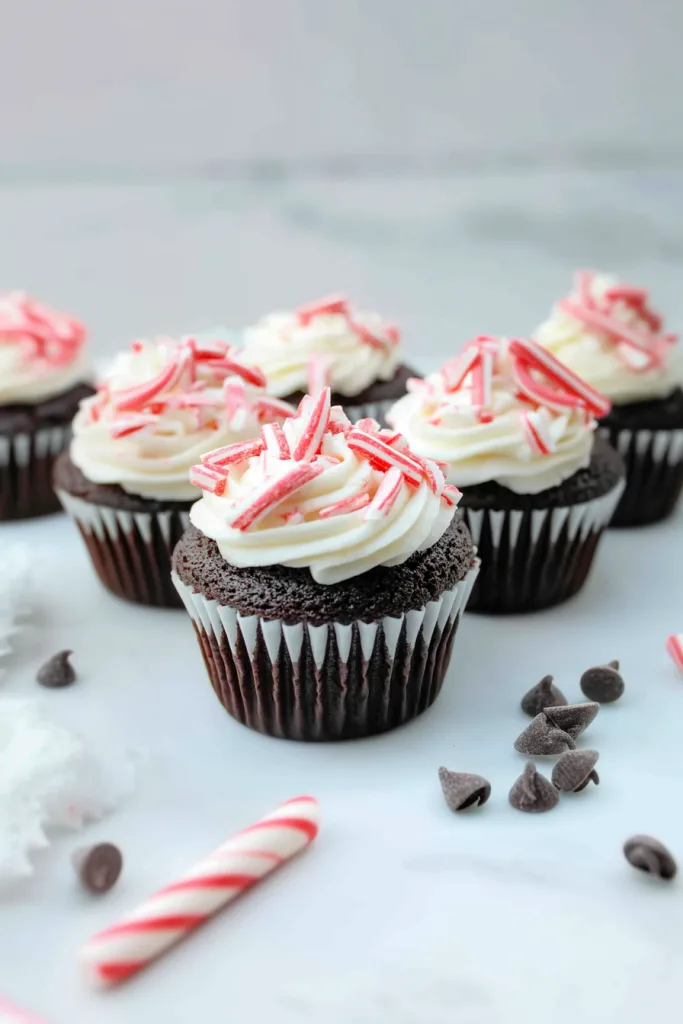 Cupcakes arranged neatly on a light surface, with peppermint fragments scattered around for a holiday touch.