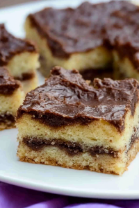 Final plated cinnamon squares showing rich contrast of dark glaze and pale cake crumb.