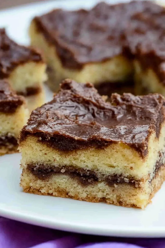 Final plated cinnamon squares showing rich contrast of dark glaze and pale cake crumb.